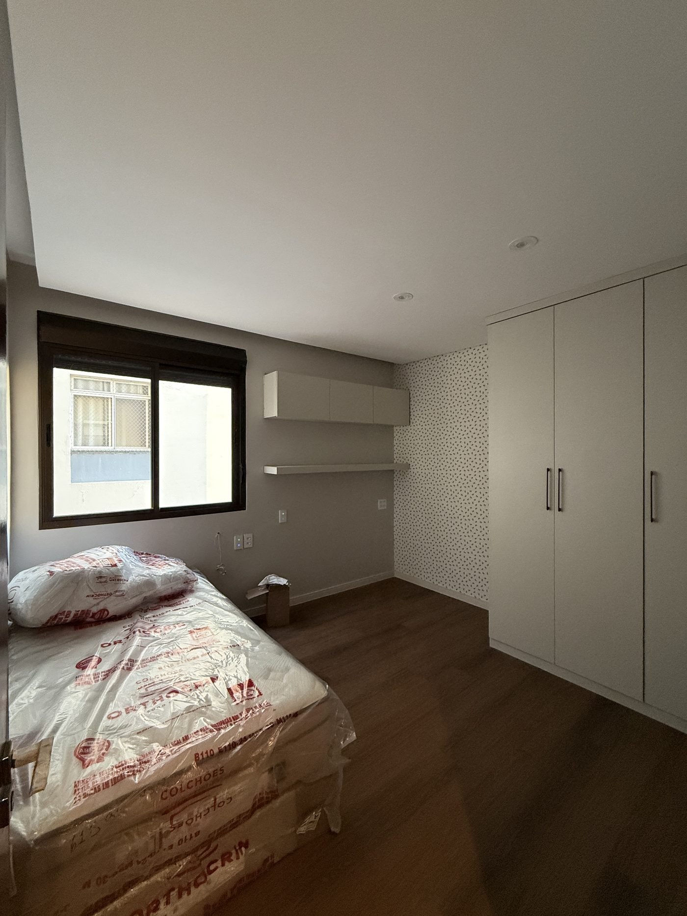Segundo quarto do apartamento com armário planejado de piso a teto e papel de parede