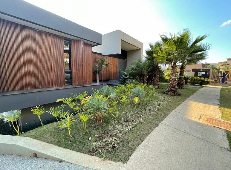 Fachada de residência em condomínio fechado de alto luxo com brise de madeira e paisagismo, obra da Apus Construtora