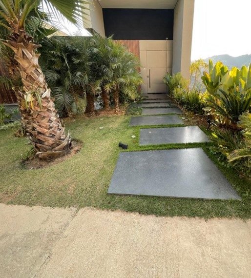 Acesso social da residência com paisagismo e caminho em placas de granito sobre grama
