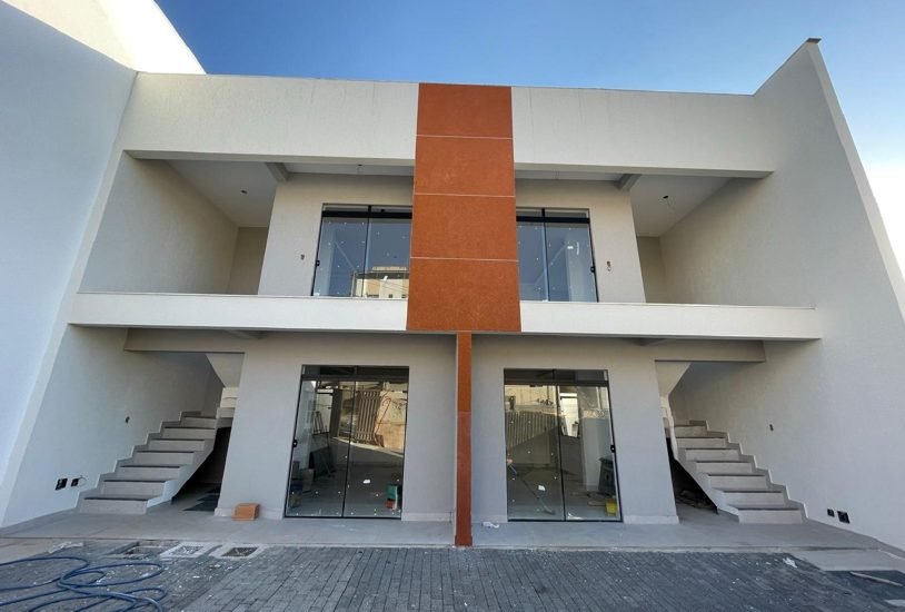 Fachada de duas casas de 130 metros quadrados em Contagem, com painel central em revestimento diferenciado e sacadas com guarda-corpo em vidro, obra da Apus Construtora