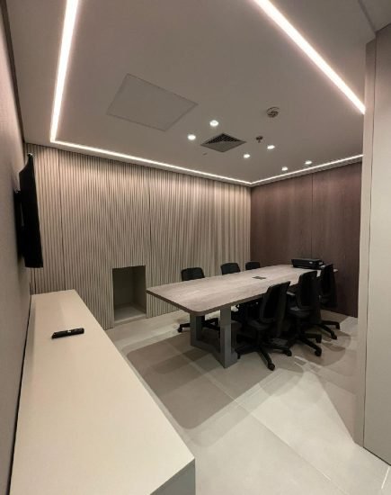 Sala de reunião do consultório com painel ripado em madeira e iluminação embutida no forro