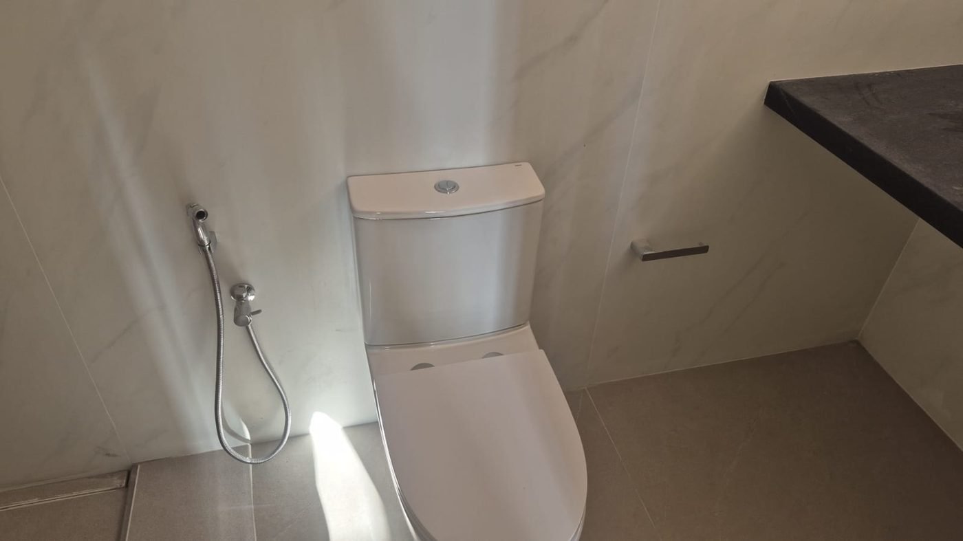 Detalhe de lavabo com revestimento em porcelanato marmorizado de grande formato e bancada em pedra escura