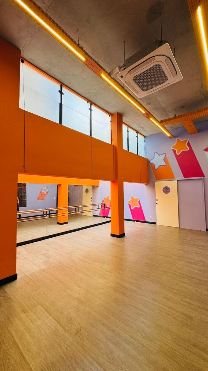 Sala de atividades com espelhos e barra em loja comercial de 600 metros quadrados na Savassi, com forro em concreto aparente e iluminação linear em bandeja metálica, obra da Apus Construtora