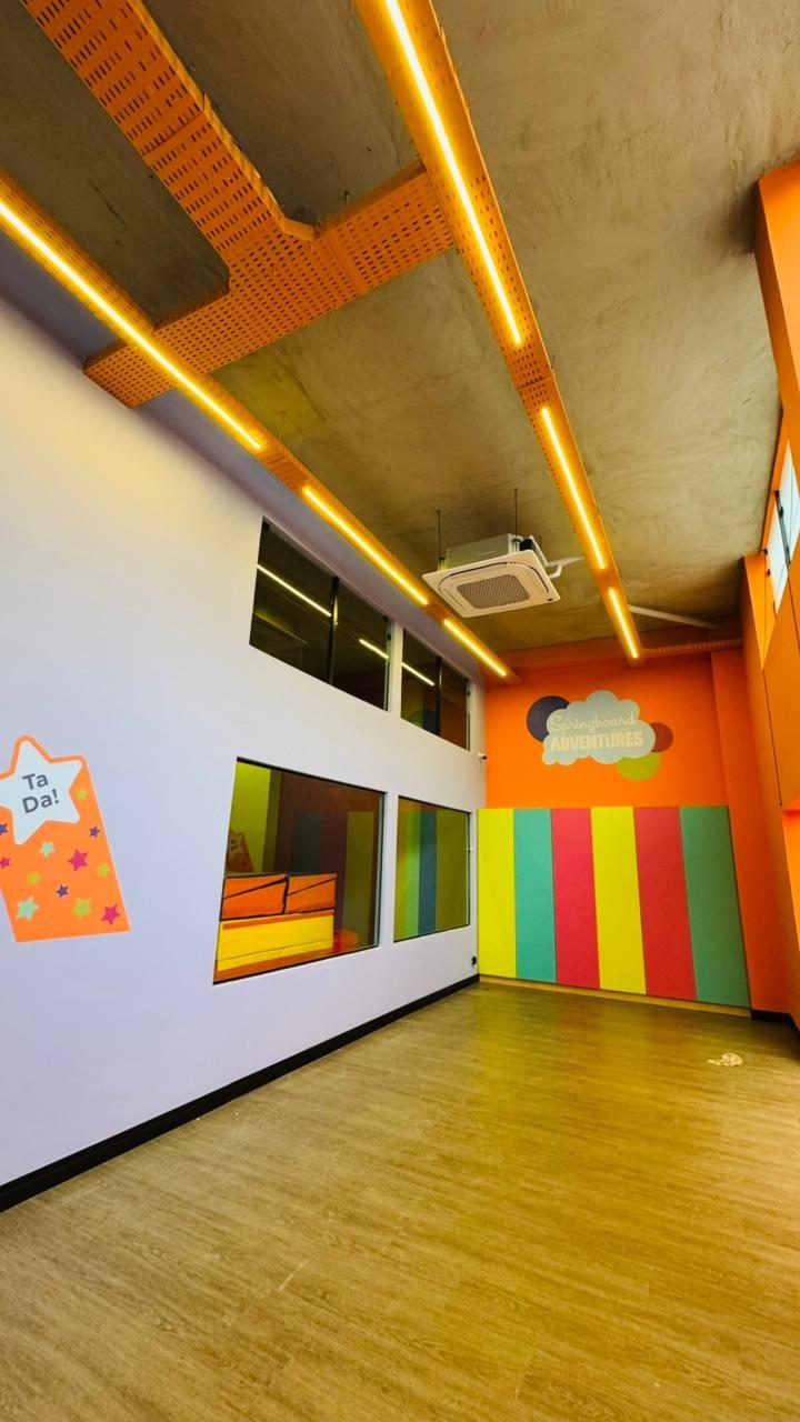 Sala lateral da loja com iluminação linear embutida em bandeja metálica aparente e forro em concreto
